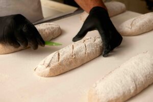Un boulanger incise la pâte avant cuisson à la Boulangerie du Marché.